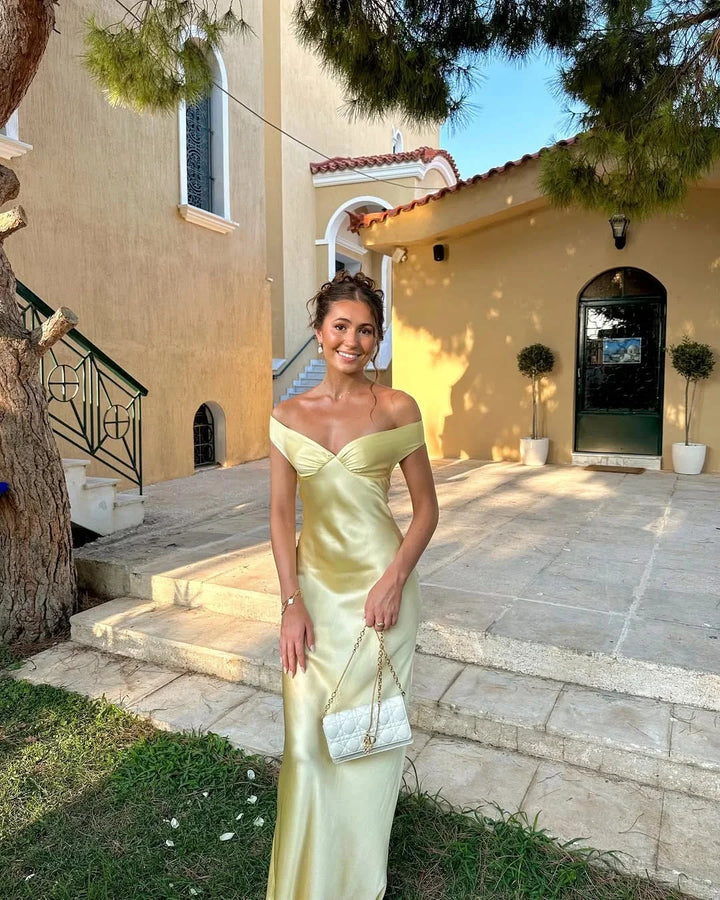 Cream off-shoulder maxi dress with clutch featuring Marvel design. Ideal for elegant occasions, made from quality material.