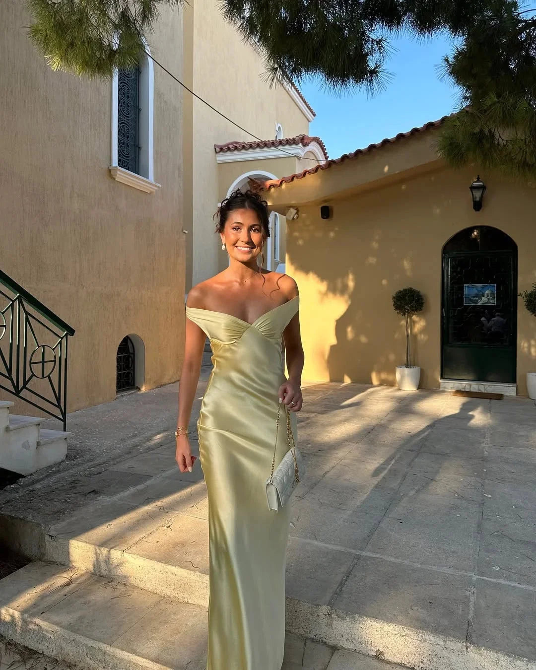 Cream off-shoulder maxi dress in Marvel fabric with matching clutch, perfect for a stylish and elegant look at any event.