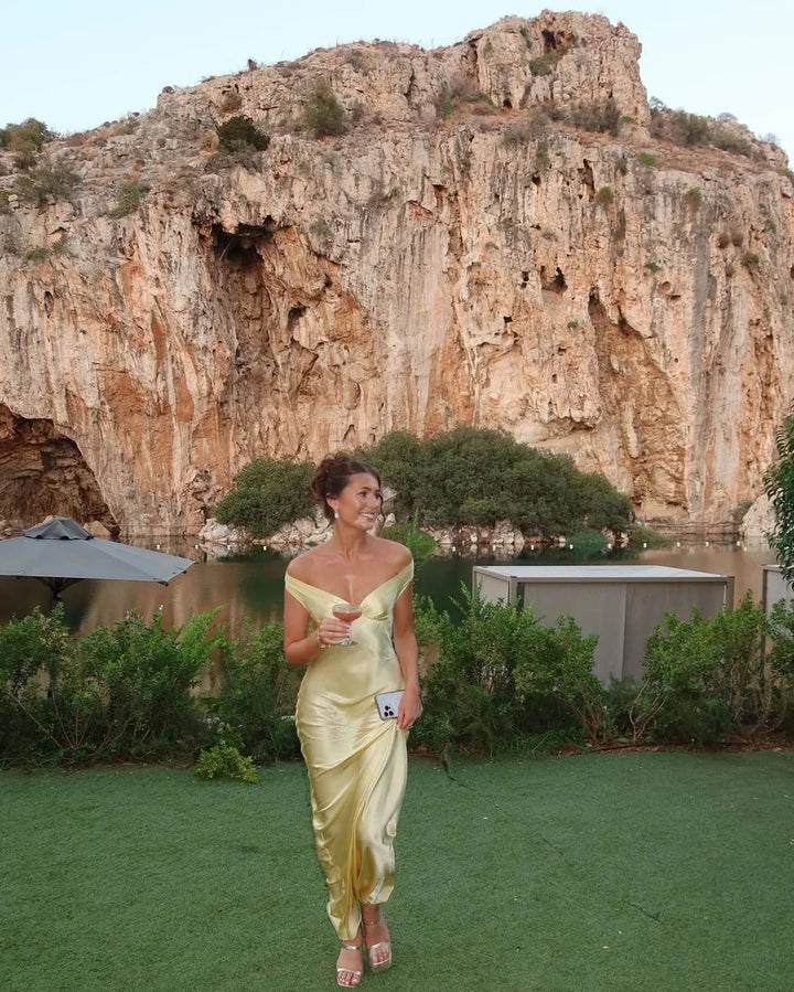 Cream maxi dress with off-shoulder design by Marvel, paired with a matching clutch. Perfect for elegant occasions with a…