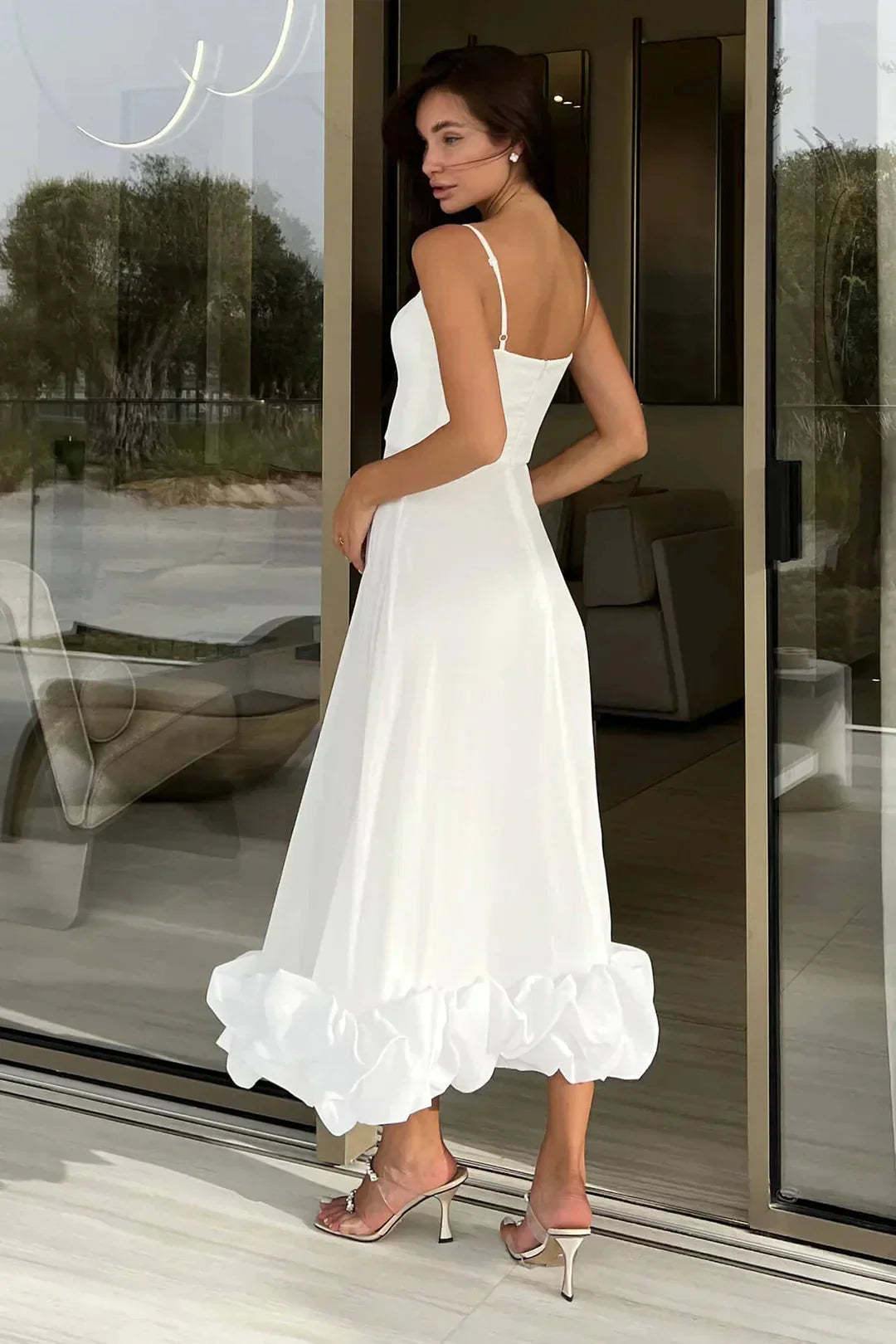 White midi dress made of soft cotton with elegant ruffle detail at the neckline and hem, perfect for a chic summer look.