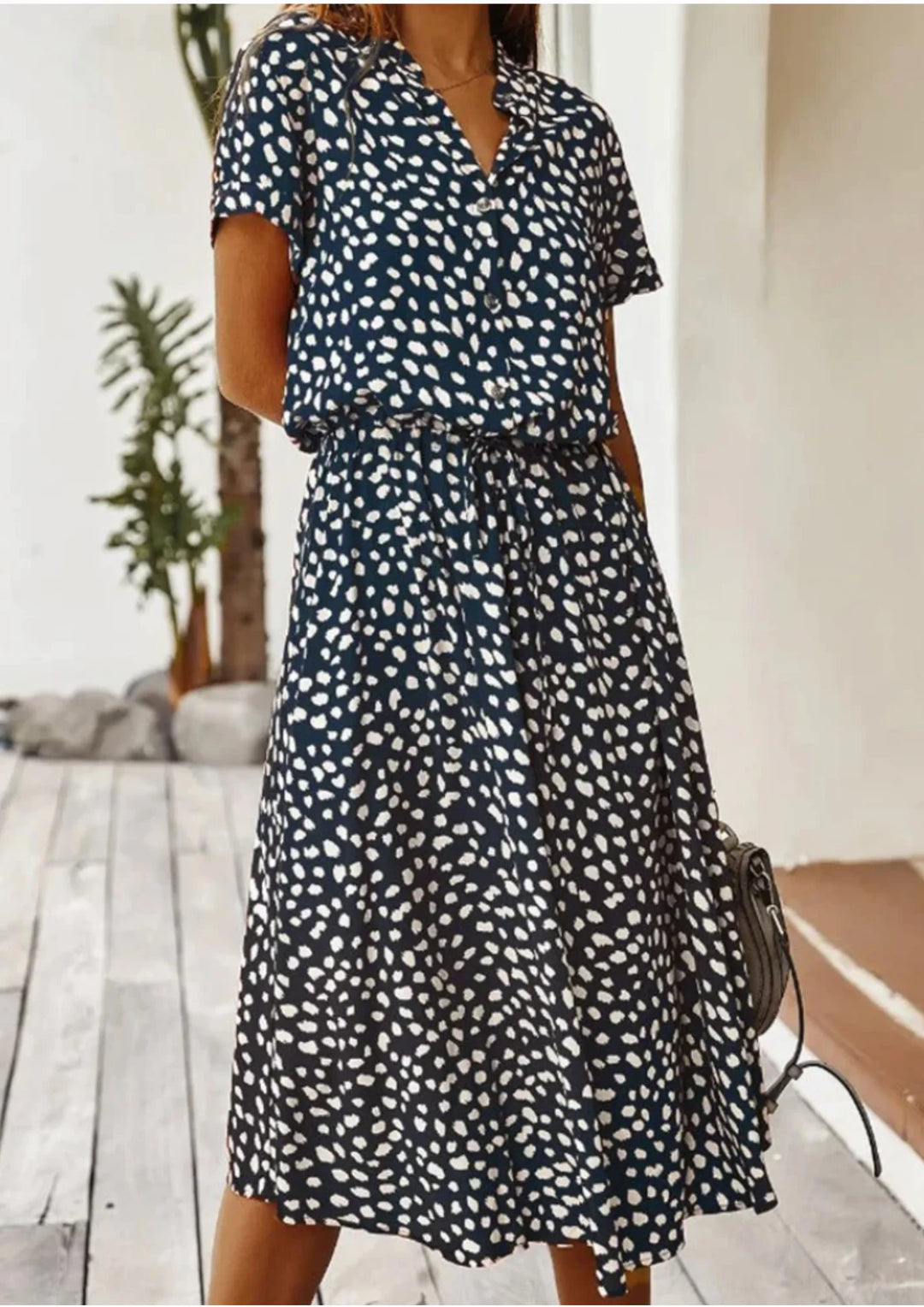Navy blue midi dress with white polka dots and waist tie, perfect for a casual yet stylish look.