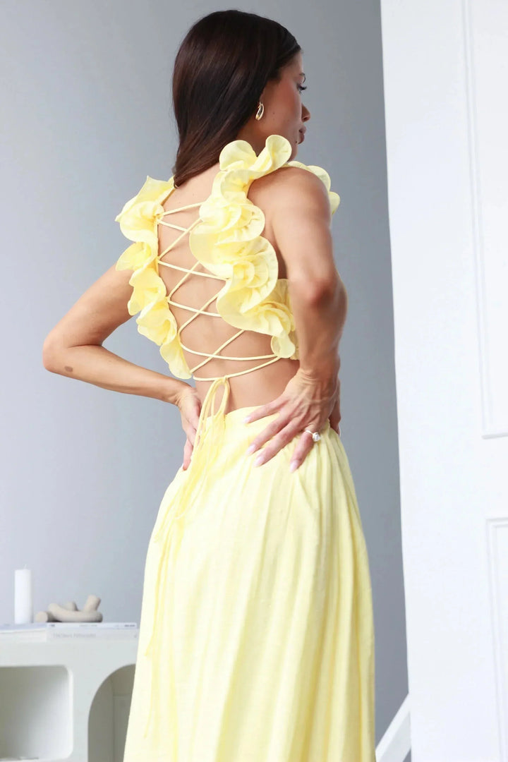 Yellow maxi dress featuring floral shoulder accents, made from lightweight airy fabric for casual elegance.