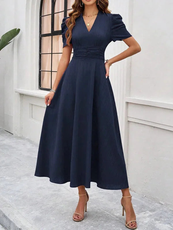 Navy midi dress with puff sleeves, V-neck, and flowy silhouette. Made from a soft, lightweight material for a comfortable…