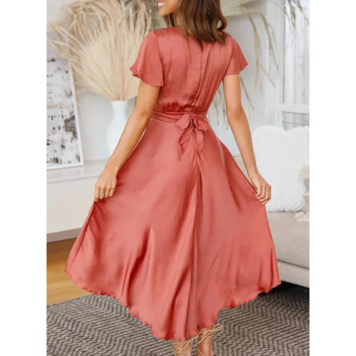 "Asymmetric midi dress in navy blue with flutter sleeves, perfect for casual events or outdoor parties."