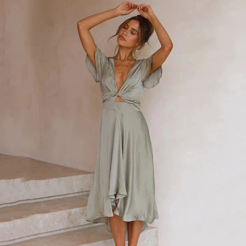 Green Nahia midi dress with flutter sleeves, asymmetrical hem, and a flattering silhouette. Made from flowy and lightweight…