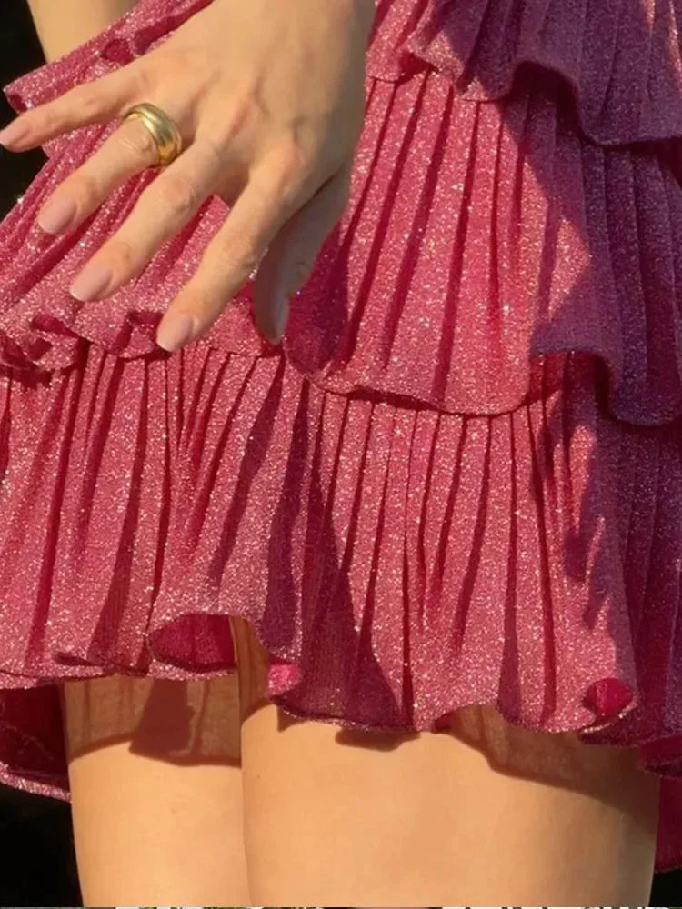 Pink shimmering ruffle dress with star details, perfect for a festive occasion or special event. The dress features a…