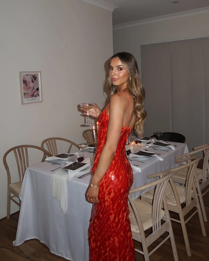 Red sequin maxi dress with deep neckline, perfect for a glamorous night out. Sparkling sequins catch the light beautifully.