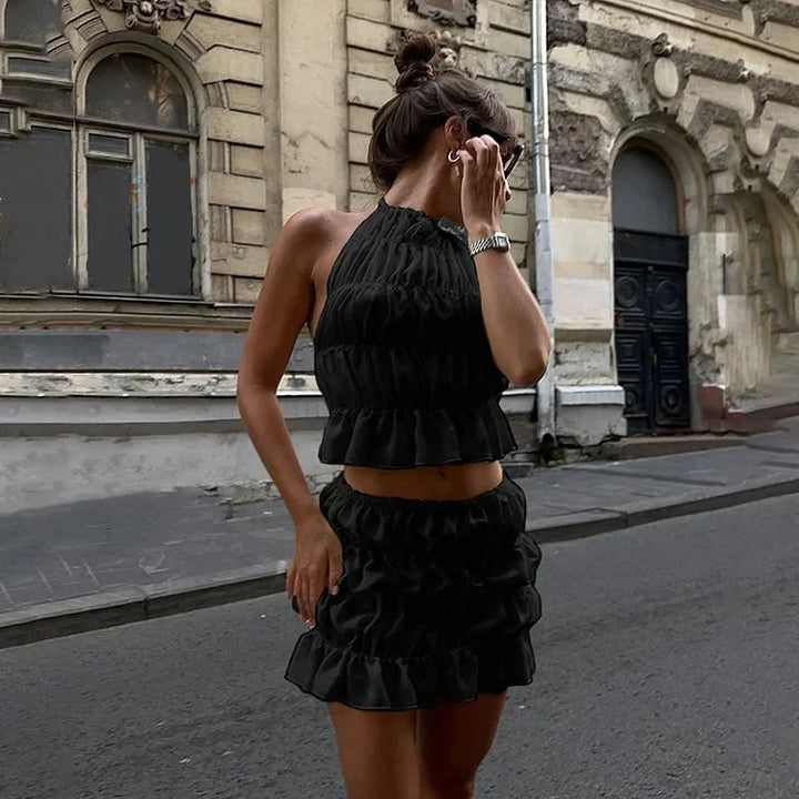 "Pleated two-piece outfit with halter neckline in soft, flowing fabric, creating an elegant and stylish look for any…