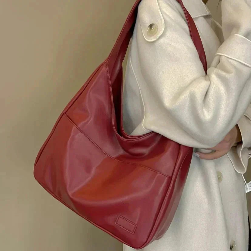 Black faux leather shoulder bag with a sleek minimalist design, featuring a structured shape and adjustable strap by Posie.