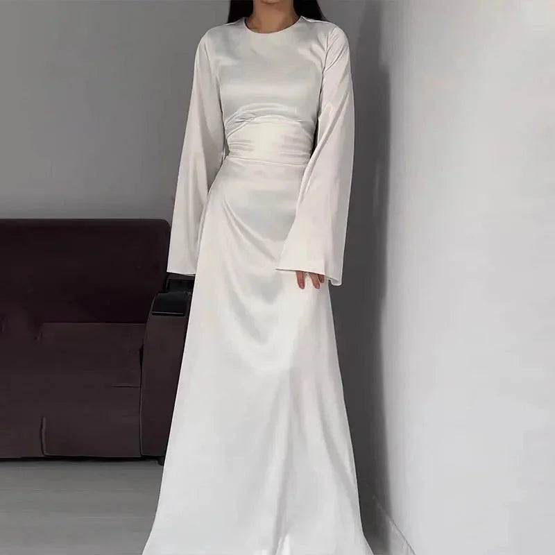 White floor-length dress with bell sleeves made of soft flowing fabric. Minimalistic design perfect for special occasions.