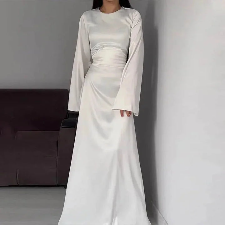 White floor-length dress with bell sleeves made of soft flowing fabric. Minimalistic design perfect for special occasions.