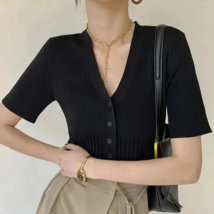 Black fitted knit cardigan with buttons by Rhoda. Textured ribbed knit design, elegant silhouette, versatile styling for…