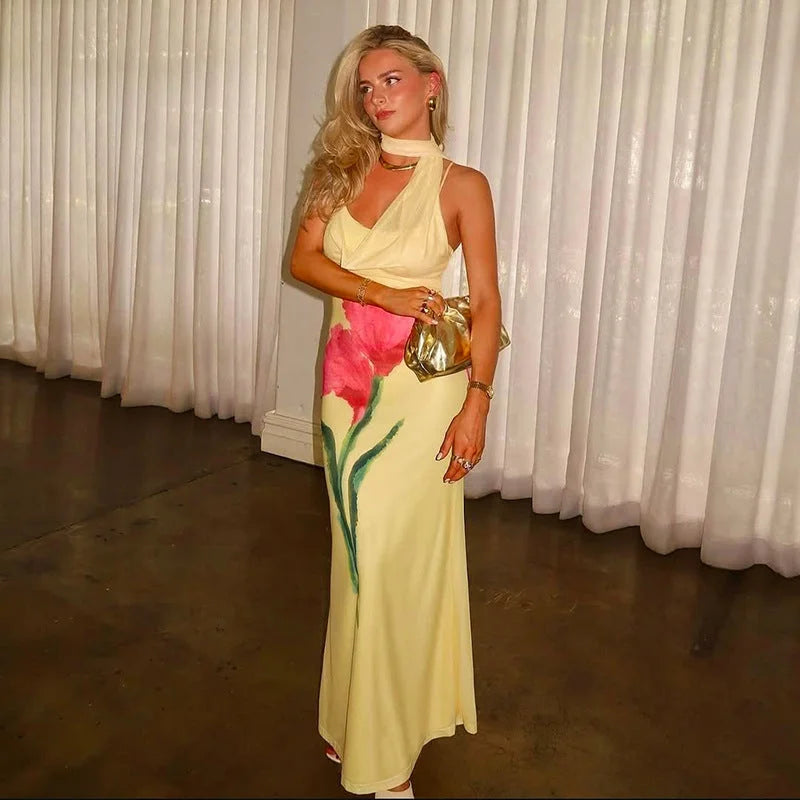 Yellow floral maxi dress with halter neck, perfect for summer outings. Features a vibrant floral pattern on flowy fabric.
