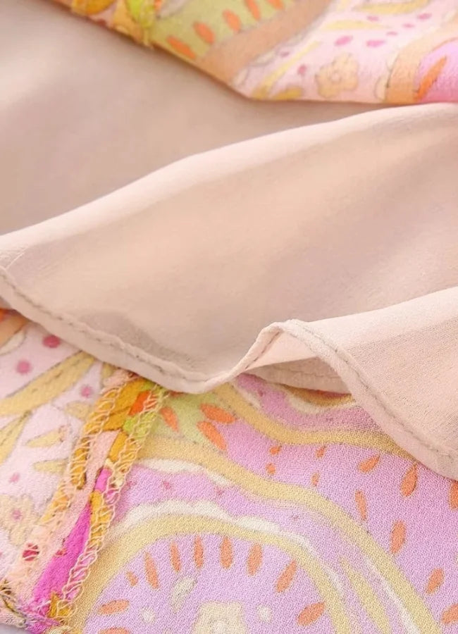 Pink and yellow patterned mini dress with V-neck, made of lightweight fabric in a stylish design.