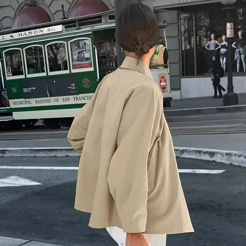 Beige oversized trench coat with button-up front, featuring a classic design, made from high-quality cotton blend fabric.