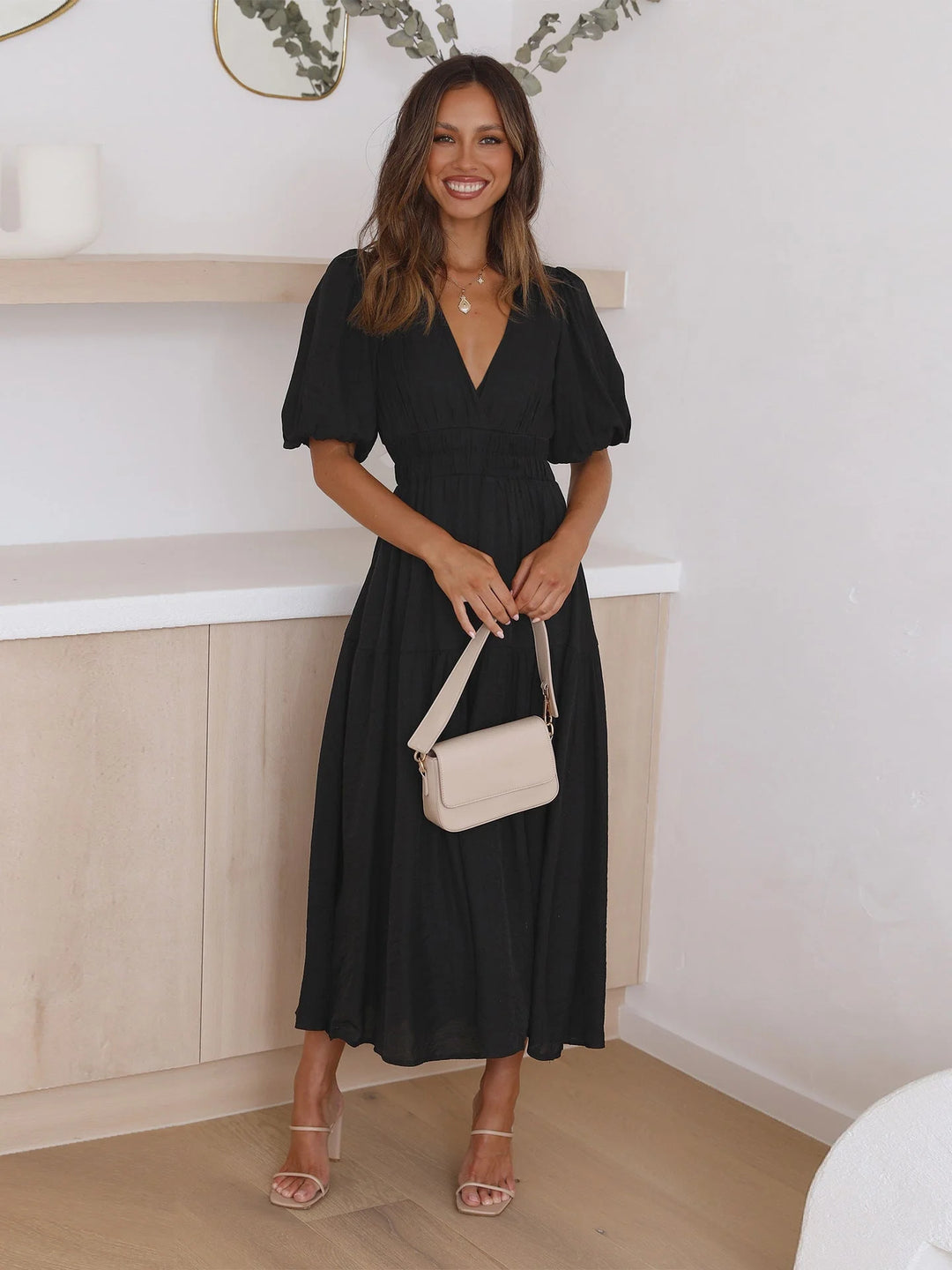 Black V-neck midi dress with elastic waist, perfect for casual chic. Made from comfortable and durable fabric with a trendy…