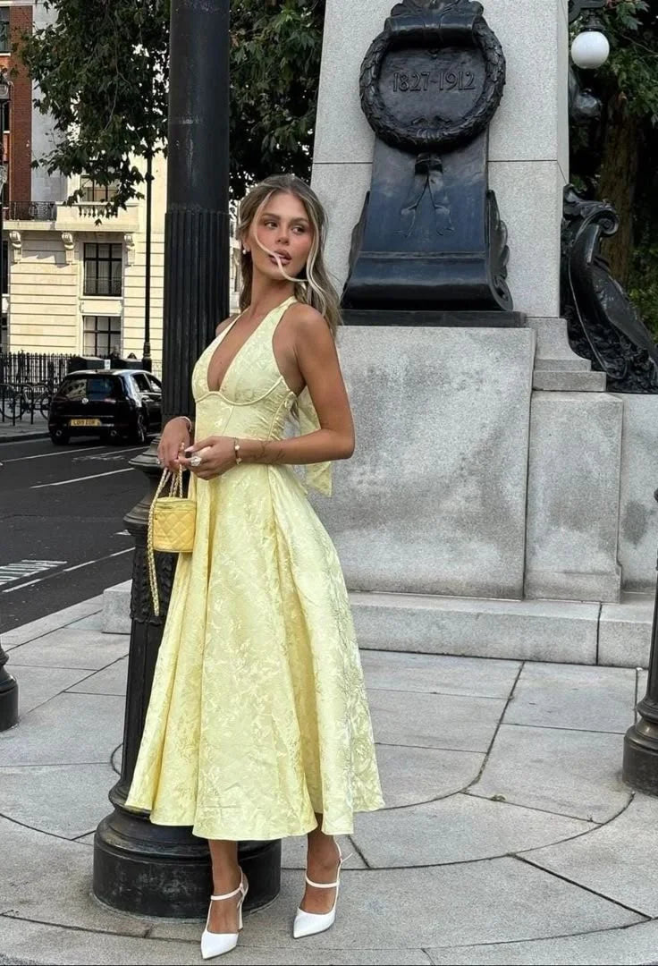 Yellow halter dress with pleated skirt in a lightweight drapey fabric, perfect for sunny days.