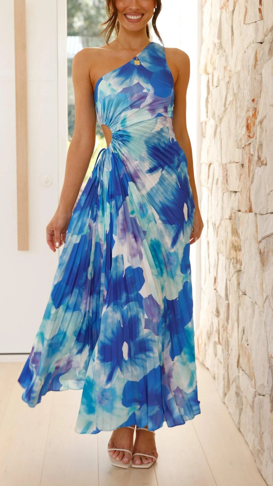 Blue floral pleated maxi dress with asymmetrical design, featuring a lightweight flowy fabric perfect for a casual or…