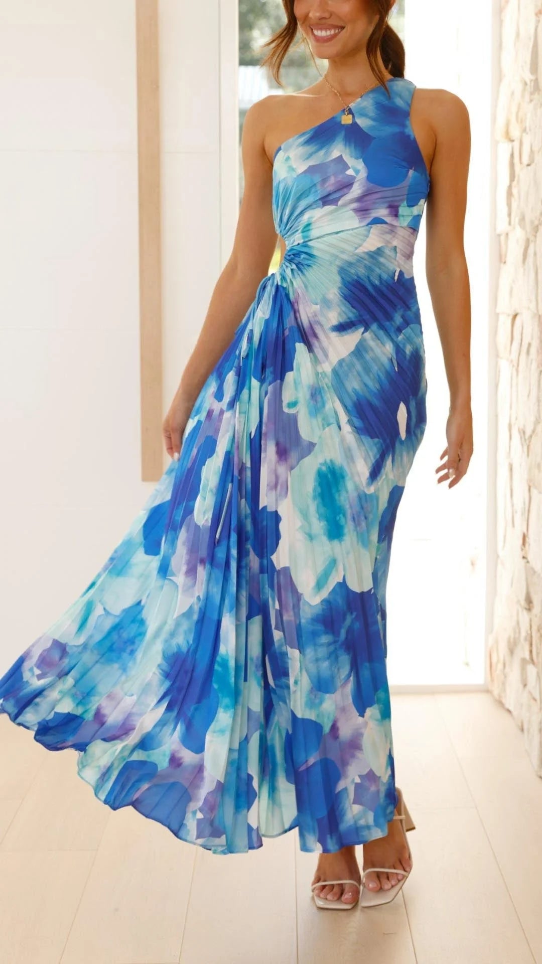 Blue floral pleated maxi dress with asymmetrical design, made with lightweight chiffon fabric, perfect for a chic and casual…