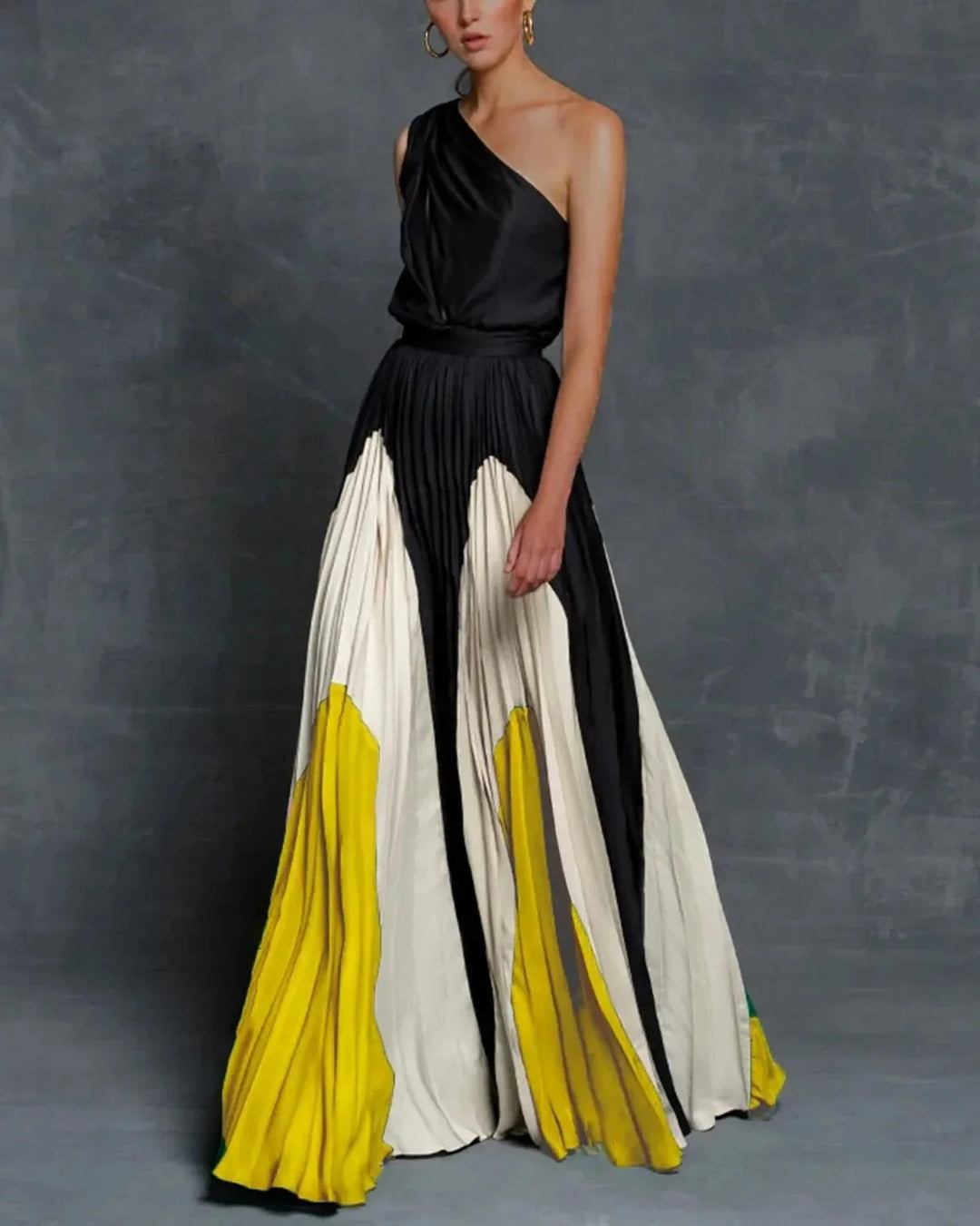 Yellow one-shoulder pleated maxi dress by Wrenna, showcasing a graceful design with a single shoulder strap and pleats.