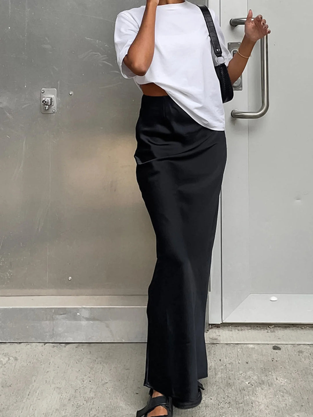 "Black satin maxi skirt with flowy design, perfect for an elegant evening look."